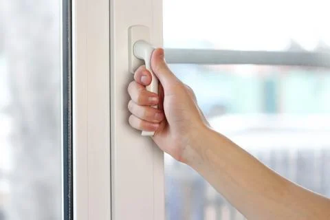 A man's hand opens a white plastic window. Close up Stock-Fotos