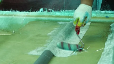 A man's hand with a paint roller applies adhesive to the fiberglass Stock Footage 203940024
