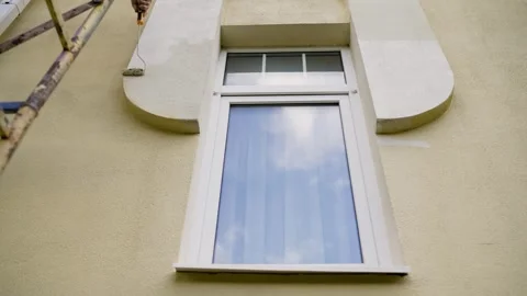 A man's hand paints the facade of a house with a roller. Stock Footage 339280446