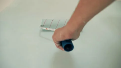 A man's hand paints the wall with a roller Painting the wall with blue paint Dad Stock Footage 153201006