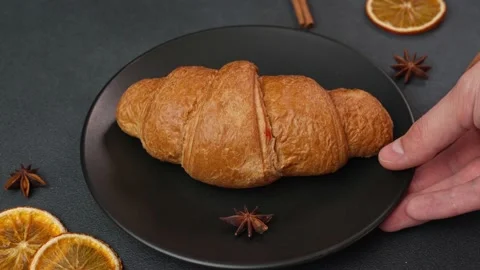 A man's Hand Picking up a black Plate from the table with a Croissant Stock-Footage 237313432