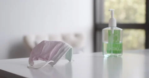 Man's hand picking up face mask from table handsanitizer in background 動画素材 130669959