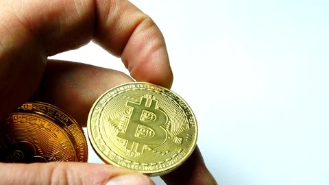 Mans hand picking up a gold btc bitcoin cryptocurrency coin, looking at it Stock Footage 85681960