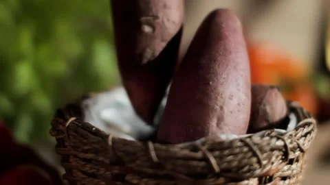 Mans hand picking a sweet potato from a basket of fresh vegetables Stock Footage 314624980