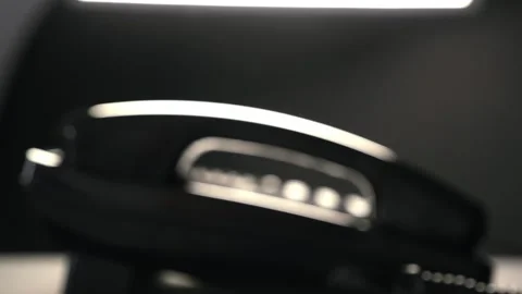 A man's hand picks up the handset of a shiny black push-button telephone 動画素材 287957381