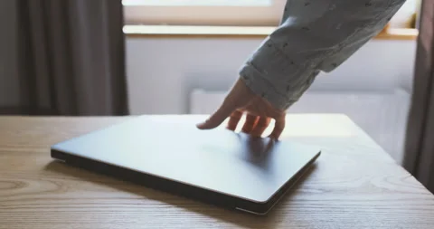 Man's hand picks up laptop lying on the table. Close-up, indoors. Concept of Stock Footage 201951017