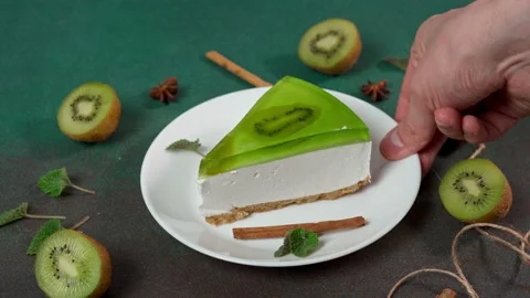 Man's Hand Picks up plate with Slice of Cheesecake with Kiwi Stock Footage 236412914