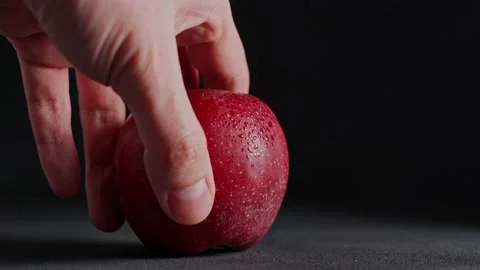 A Man's hand Picks up a red Apple from the table against a black background Stock Footage 235196164