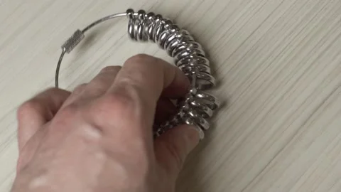 A man's hand places a wedding ring size measuring tool on the table. Stock Footage 153548200