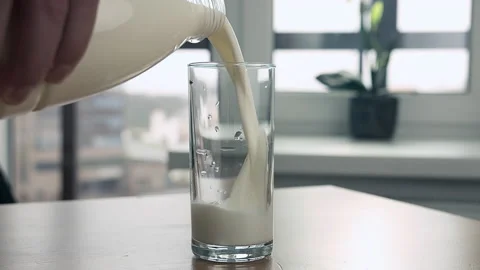 Man's hand with a plastic bottle pours milk into a glass Stock Footage 158376943