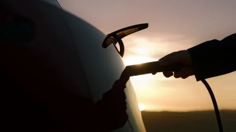 Man's hand plugging in charging cord in electric vehicle in car charging socket Video stock 170859514