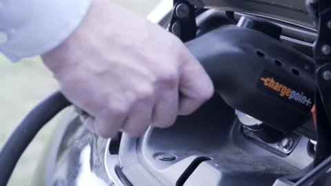 Mans hand plugging in elecrtic car charger Stock Footage 146278289