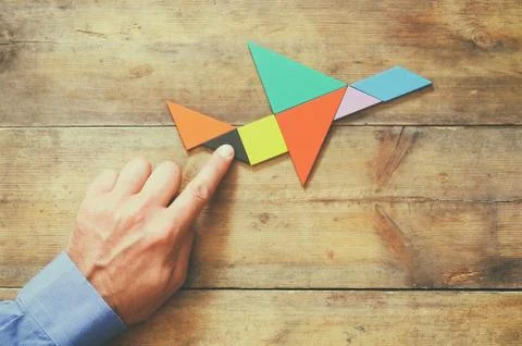 Man's hand pointing at plane made from tangram puzzle Stock Photos