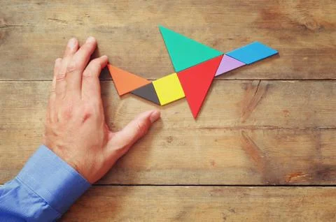 Man's hand pointing at plane made from tangram puzzle Stock Photos