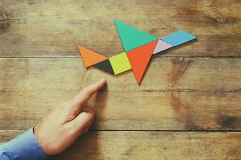 Man's hand pointing at plane made from tangram puzzle Stock Photos
