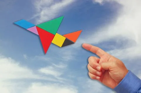 Man's hand pointing at plane made from tangram puzzle Stock Photos
