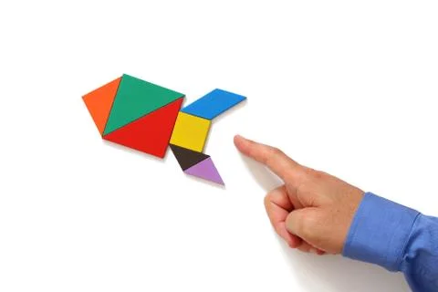 Man's hand pointing at rocket made from tangram puzzle Foto stock