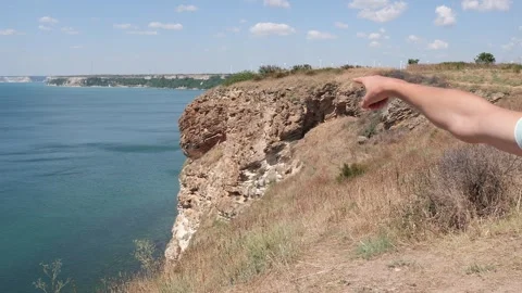 Man's hand pointing towards coastal wind farm on a sunny day 動画素材 342649669