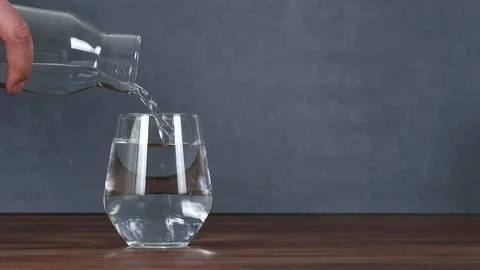 Man's hand pouring water into an empty glass cup, isolated background Stock Footage 130516166
