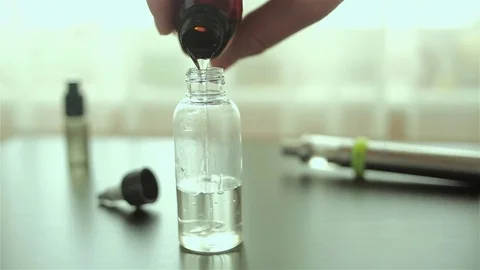 Man's hand pours a liquid for e-cigarette in the bottle. Electronic cigarette. Stock Footage 72414742