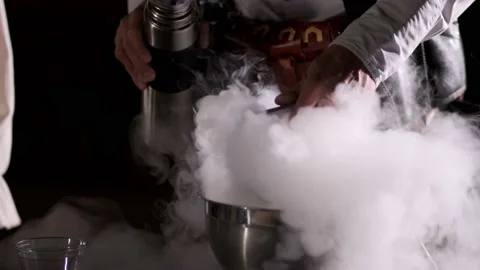 A man's hand pours liquid nitrogen into a cup and whips it with a mixer Stock Footage 168261504