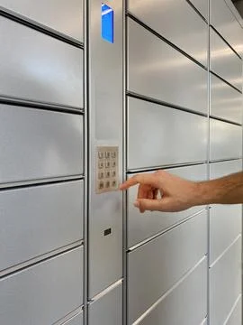 Mans hand presses code to open cell with parcel in automatic post terminal Foto stock