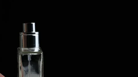 The man's hand presses on the perfume diffuser on a black background. Copy space Vidéo 151407582