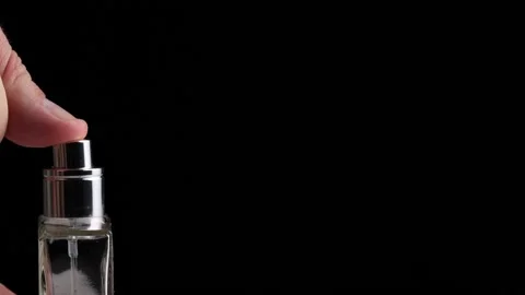 The man's hand presses on the perfume diffuser on a black background. Copy space Vidéo 157756201