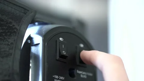 A man's hand presses power button on black light device, turns it on and off. Stock Footage 140131760
