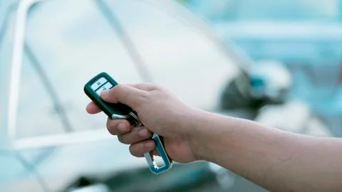 Man's hand presses on the remote control car alarm systems. Stock Photos