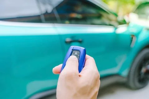 Man's hand pressing button of remote to lock or unlock the car door in car .. Stock Photos