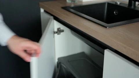 Man's hand pulling and closing a drawer with trash can at modern white kitchen Stock Footage 153289020