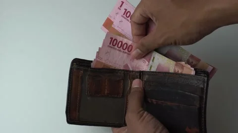 A man's hand is pulling out indonesian money rupiah in a brown leather wallet Stock Footage 222279594