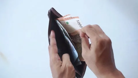 A man's hand is pulling out indonesian money rupiah in a brown leather wallet Видео 322159510