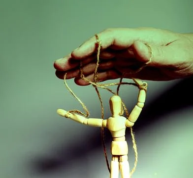 Man's hand pulling strings of wooden puppet on gray background. Concept of .. Stock Photos