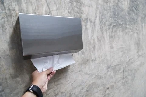 Man's hand pulling tissue to wipe his hands after using the toilet Stock Photos