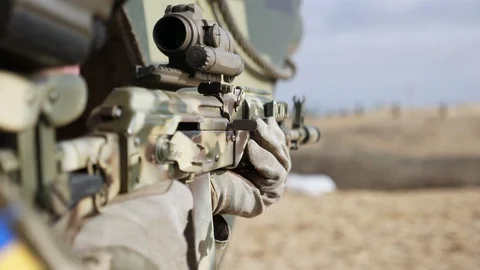 Man`s hand pulling trigger of assault gun with an optical sight in a field in 動画素材 120178621