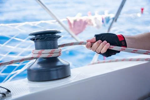 Mans hand pulling winch rope on sailing boat Stock Photos