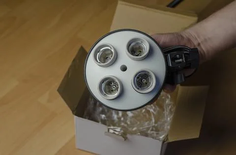 Man's Hand pulls a 4-lamp holder out of a white cardboard box. Stock Photos