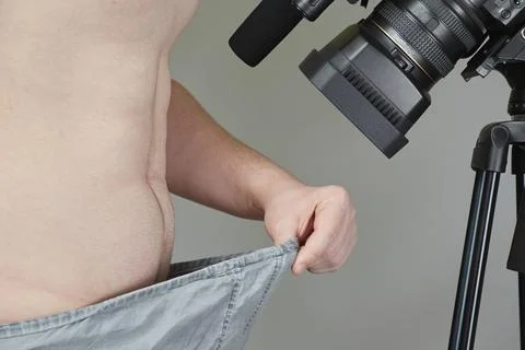Man's hand pulls off elastic band of underwear in front of video camera, priv Stock Photos