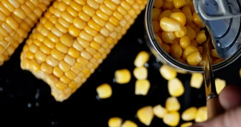 The man's hand pulls out a spoon of canned corn from cans. Stock Footage 127537521