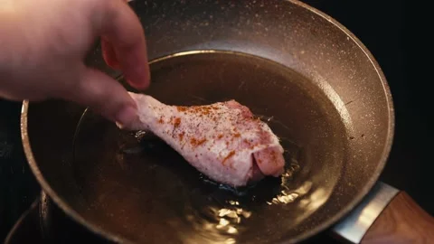 A man's hand put chicken legs and wings for frying in a pan of hot oil Stock Footage 152223979