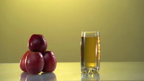 Man's hand put the glass with apple juice on the table. Nice yellow background Stock Footage 154628107