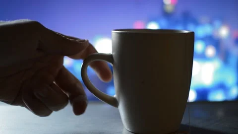 Man's hand put a mug of black hot tea on the table in a night city background. Vidéo 219928755