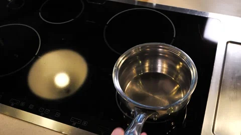 Mans hand puts and twists a saucepan on an electric stove slow motion Stock Footage 147391383