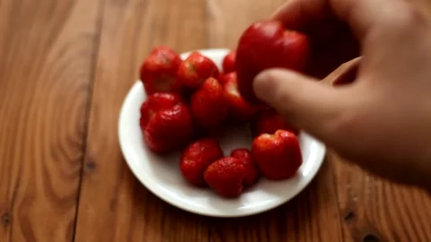 A man's hand puts a big tasty strawberry in a plate. Stock Footage 201745873