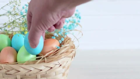 A man's hand puts an Easter egg into a basket. Stock Footage 142509031