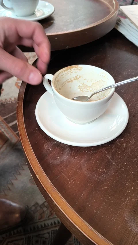 A man's hand puts a empty cup with a spoon on top of the saucer. Stock Footage 336976635