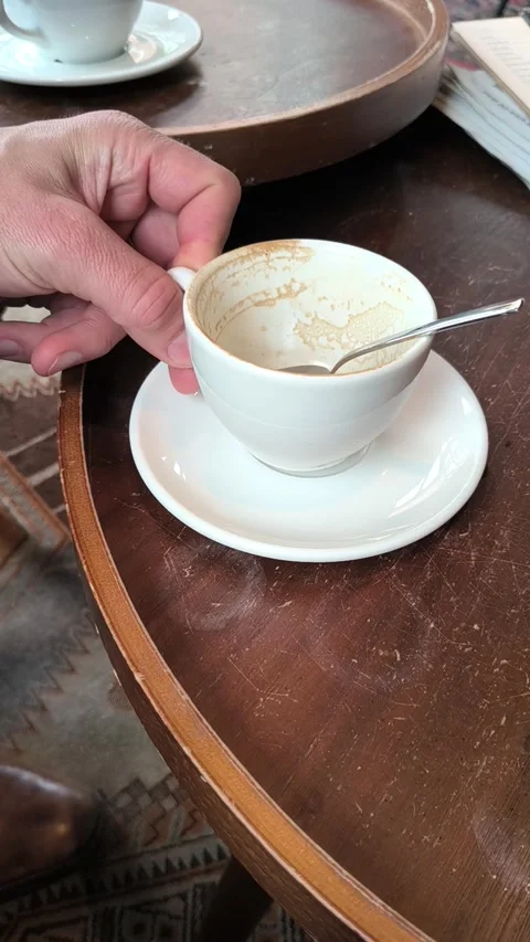 A man's hand puts a empty cup with a spoon on top of the saucer. Stock Footage 336976647