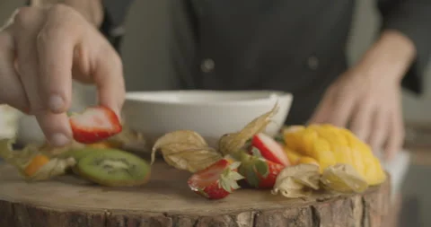 Man's hand puts half of strawberry on wooden plate. 4K slow motion video Stock Footage 103836596